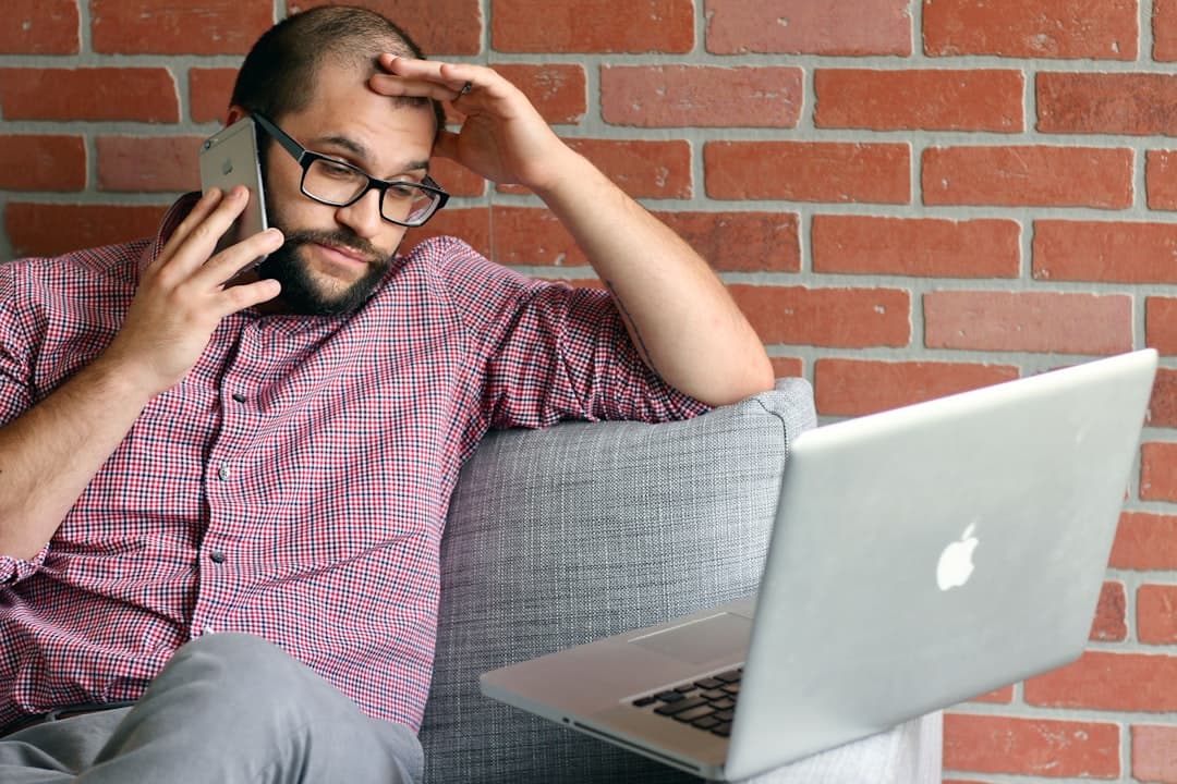 A frustrated practice owner checking their phone and laptop